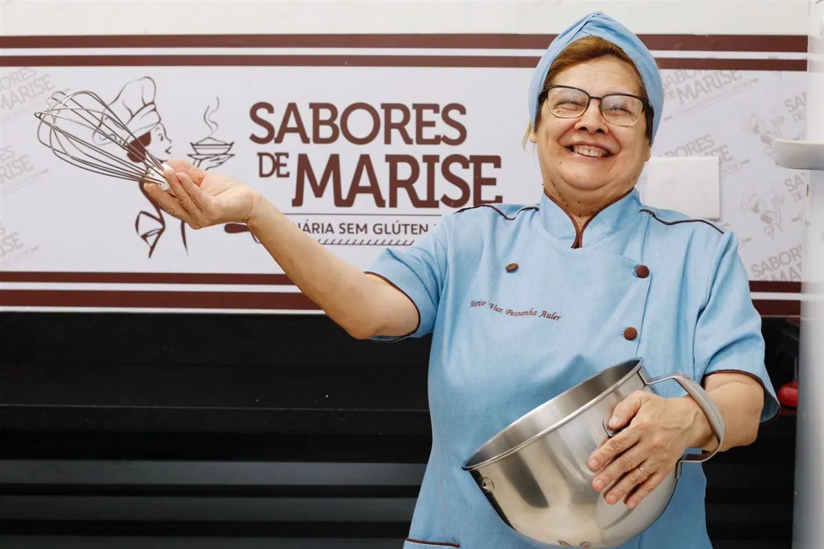 Marise sorrindo na cozinha com batedor e tigela