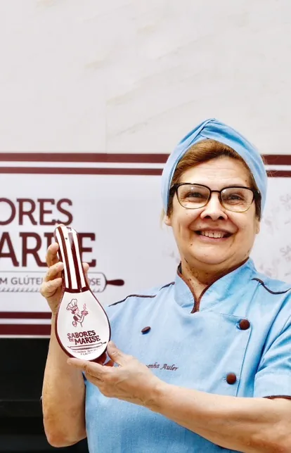 Marise segurando um descanso de colher com a marca Sabores de Marise